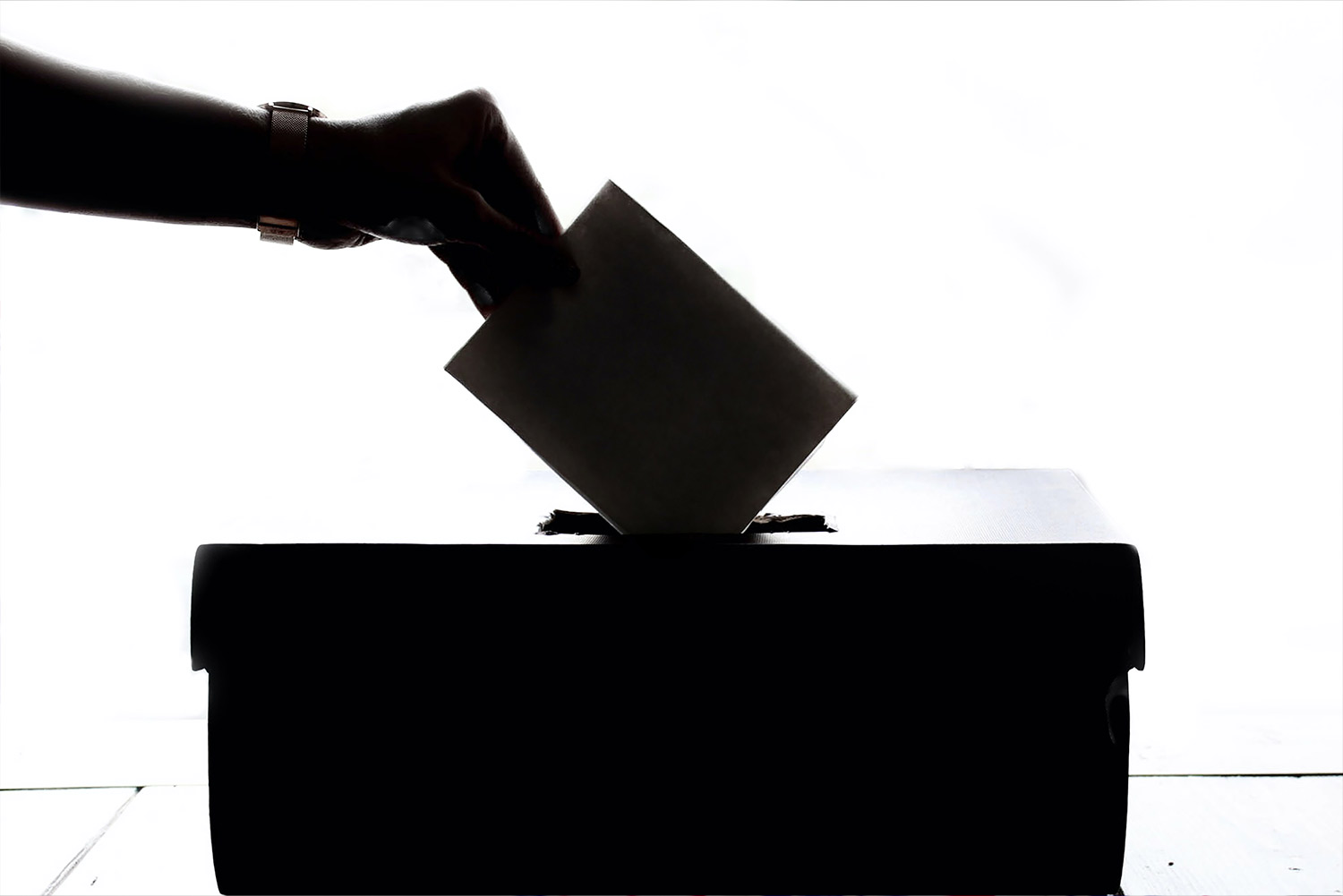 Hand Putting Envelope In A Ranked Choice Ballot Box